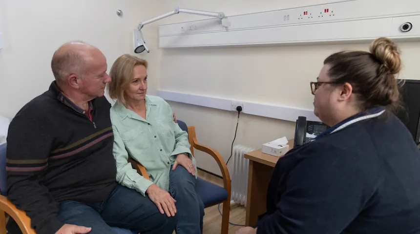 Lady and gentleman sat in chairs facing a nurse