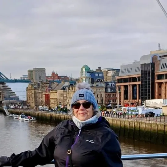 A photograph of Joyce standing on a bridge against the backdrop of the Millenium Bridge in London