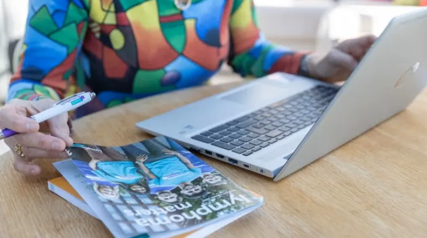 Person sat at a desk with a laptop and the Lymphoma Matters magazine