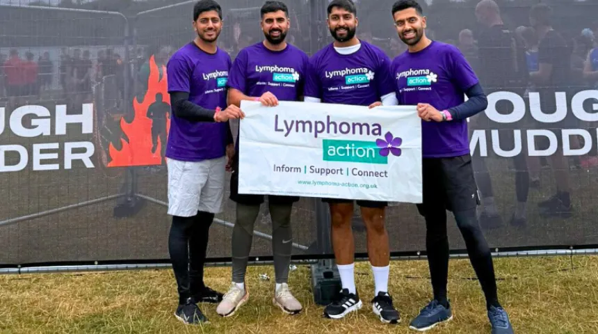 Four Lymphoma Action supporters holding a Lymphoma Action banner after completing a challenge event