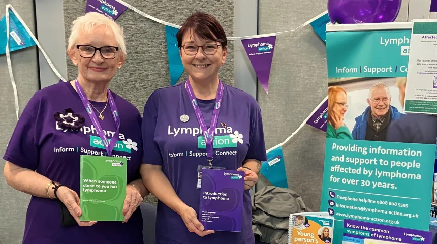 Two Lymphoma Action volunteers smiling at a stall of lymphoma information