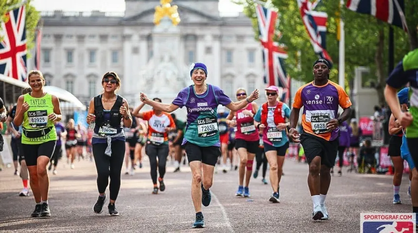 runners crossing the london marathon finish line with buckingham palace in the background